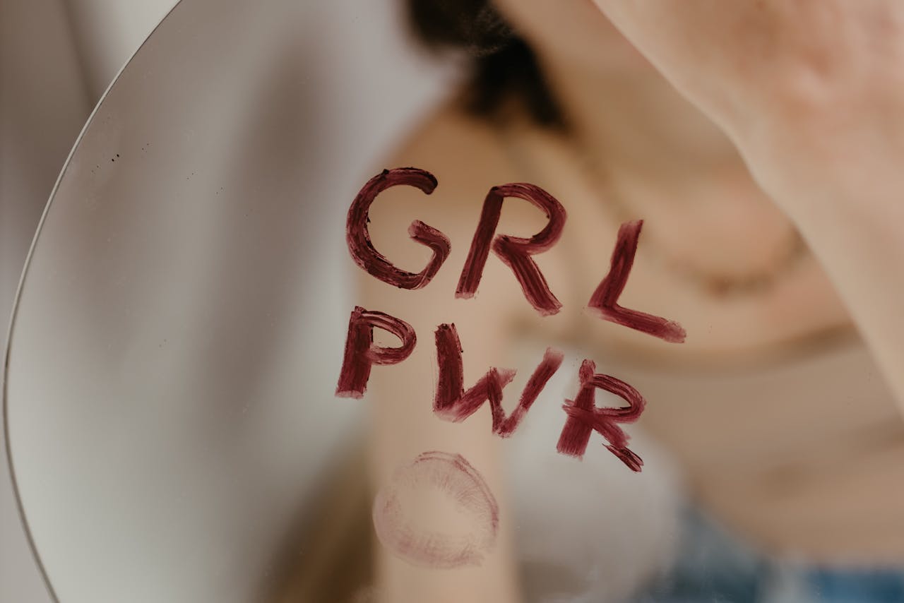 stats-img Close-up of empowering 'GRL PWR' message written on a mirror with lipstick.